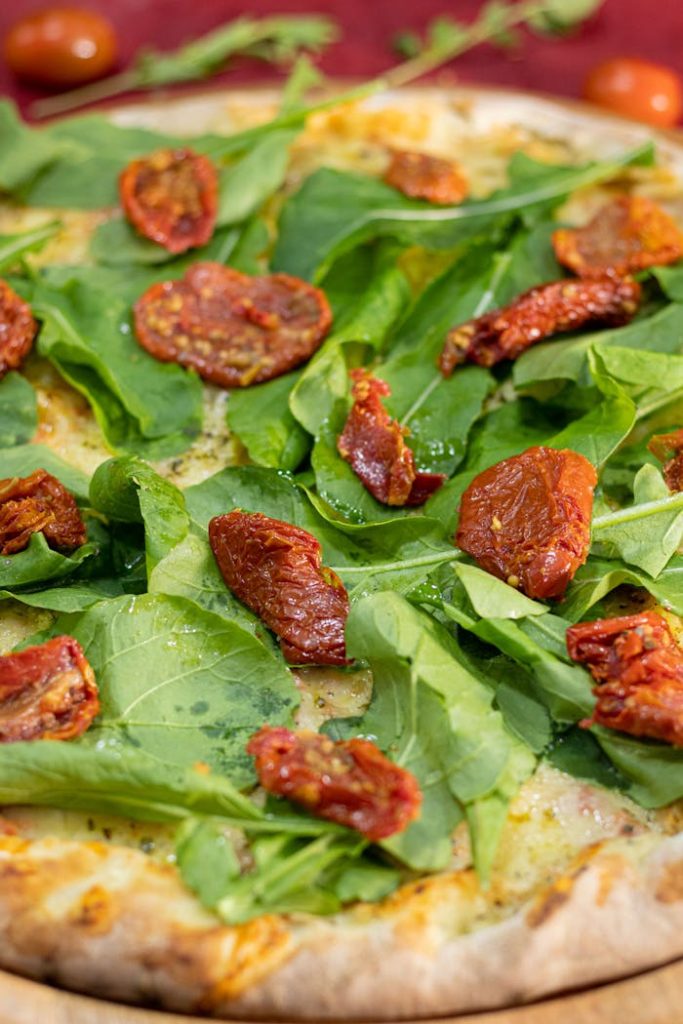 Mouth-watering pizza topped with fresh arugula and sun-dried tomatoes. Perfect for Italian cuisine enthusiasts.