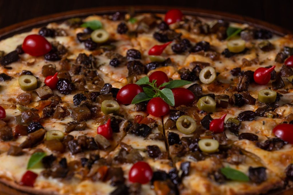 Mouth-watering Italian-style pizza topped with olives, cherry tomatoes, and cheese.